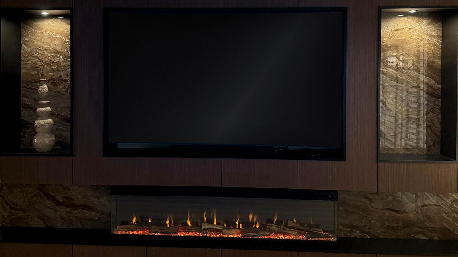 De cinewall recht van voren: donker notenhout met twee verlichte natuurstenen nissen, verzonken televisie en de lijnhaard over de volle breedte