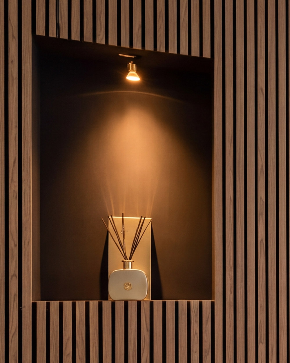 De verlichte nis in de lattenwand, met een spot die het hout warm aanlicht